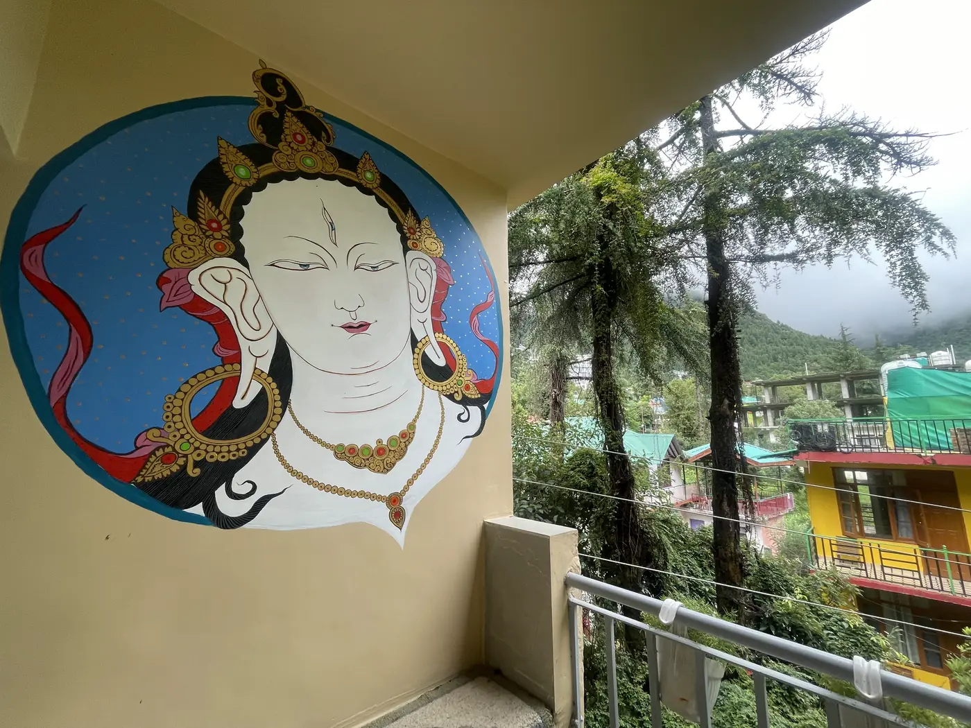 A painted mural on the balcony wall, the railing opening onto conifers