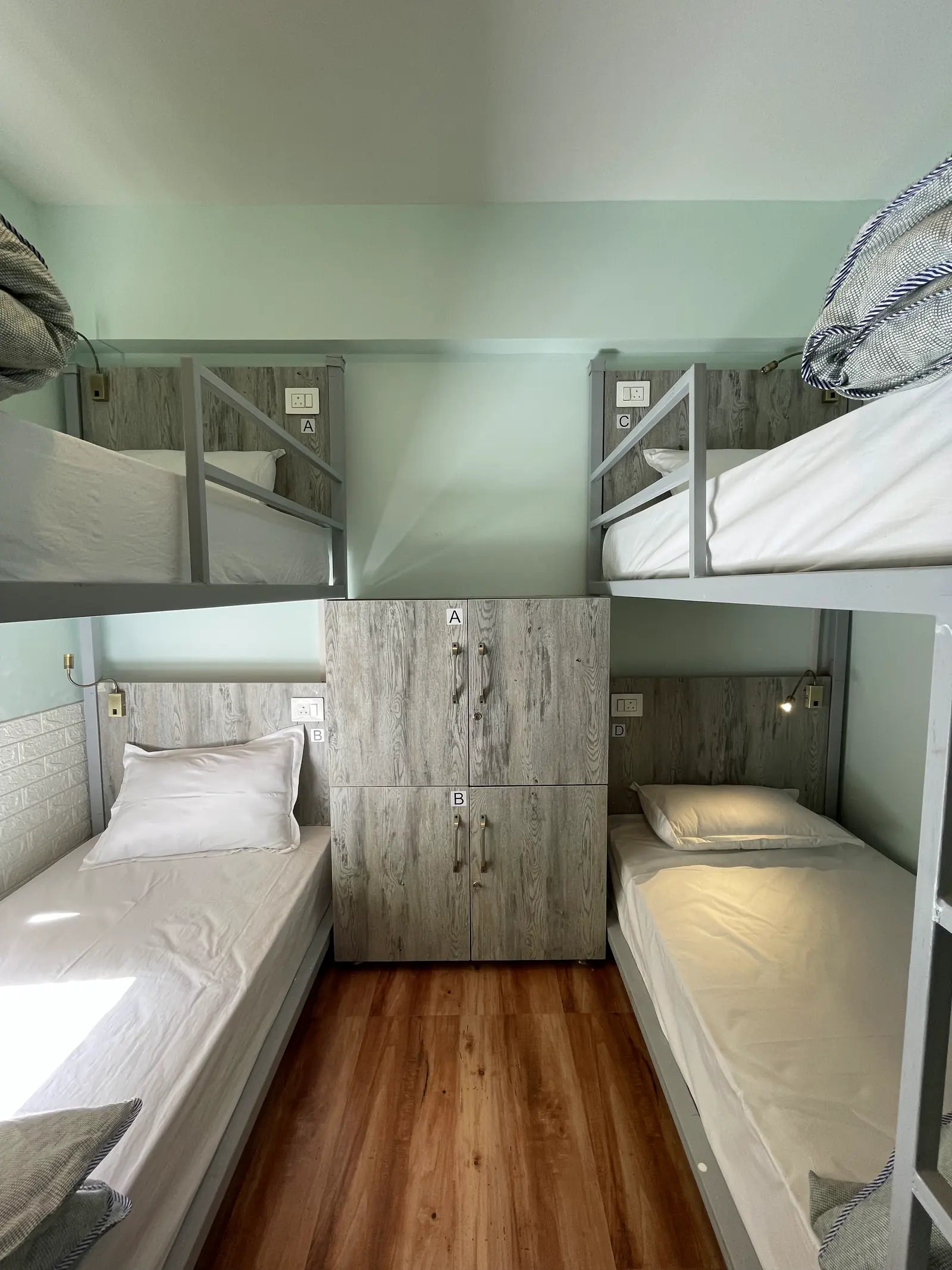 The four-bed dorm, two bunks facing each other across a lettered locker unit