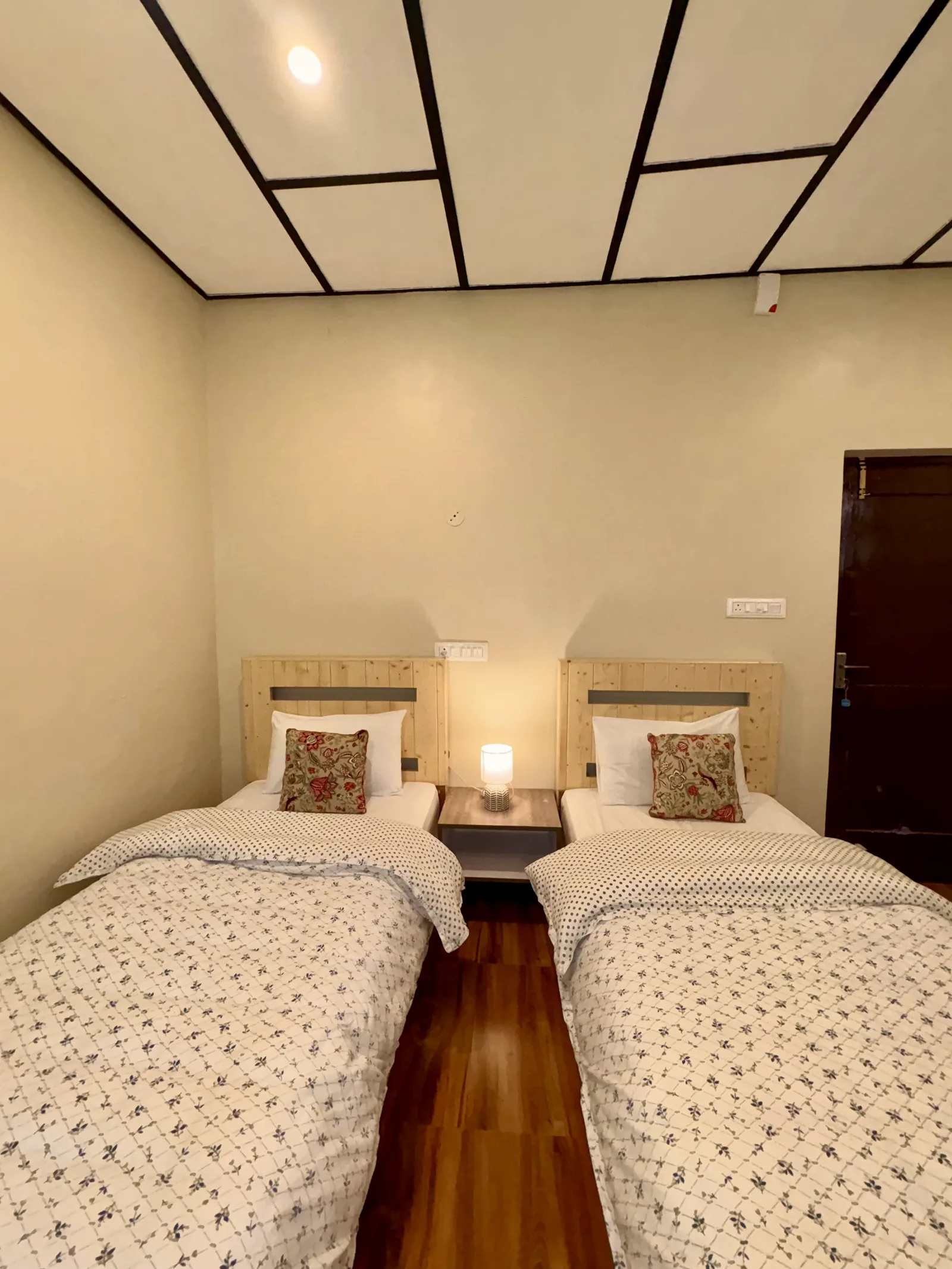 An Evolve Home deluxe twin room, two single beds either side of a lit bedside lamp