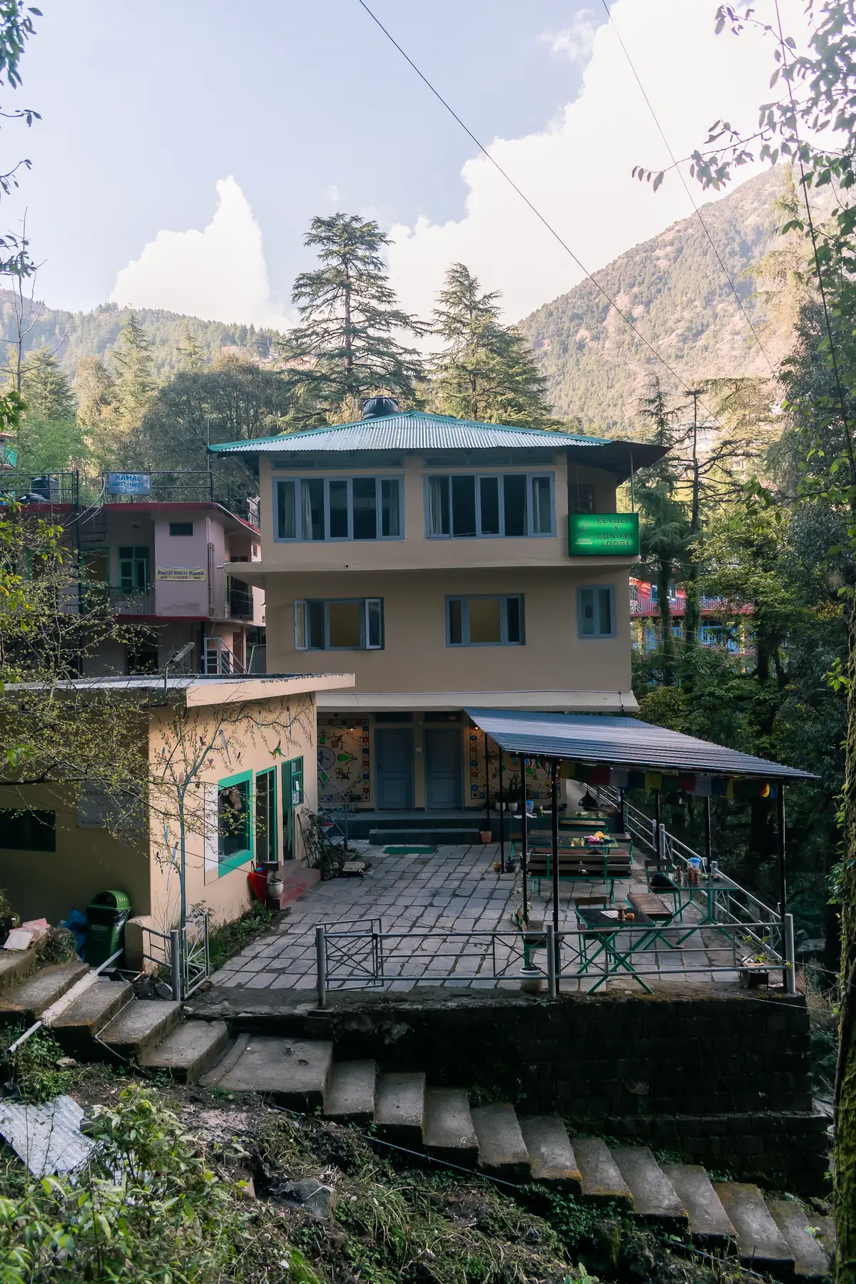 The house seen from the front, benches set out on the paved terrace beneath it
