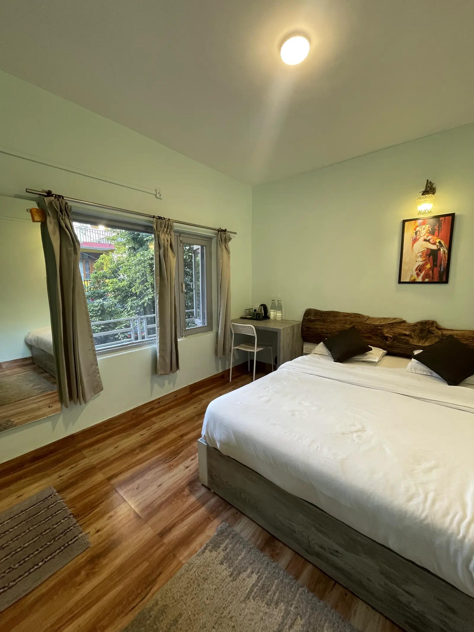 A king room with a log headboard, a desk and rugs on the wooden floor