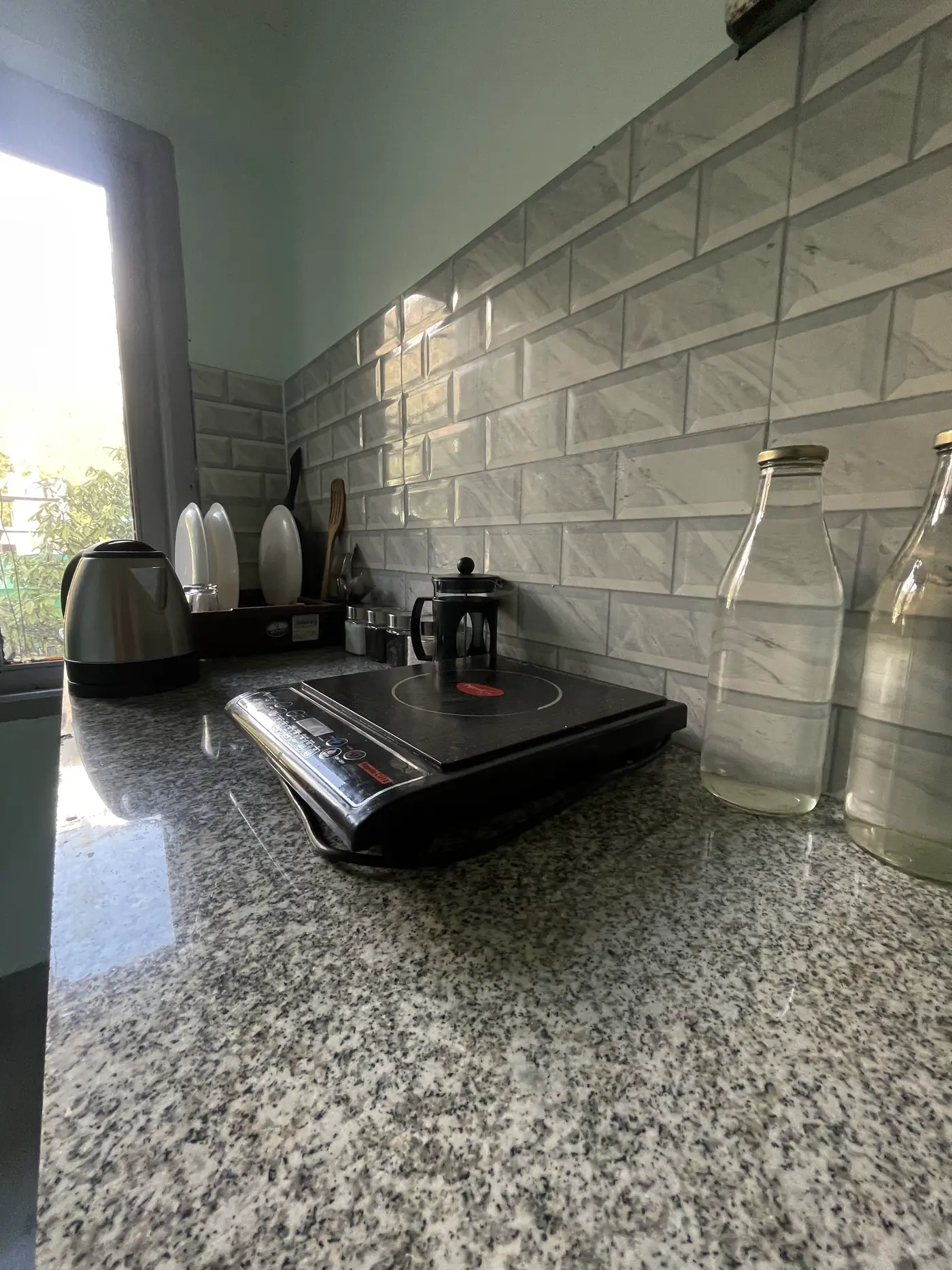 A kettle, French press and glass bottles set out on the counter in a room