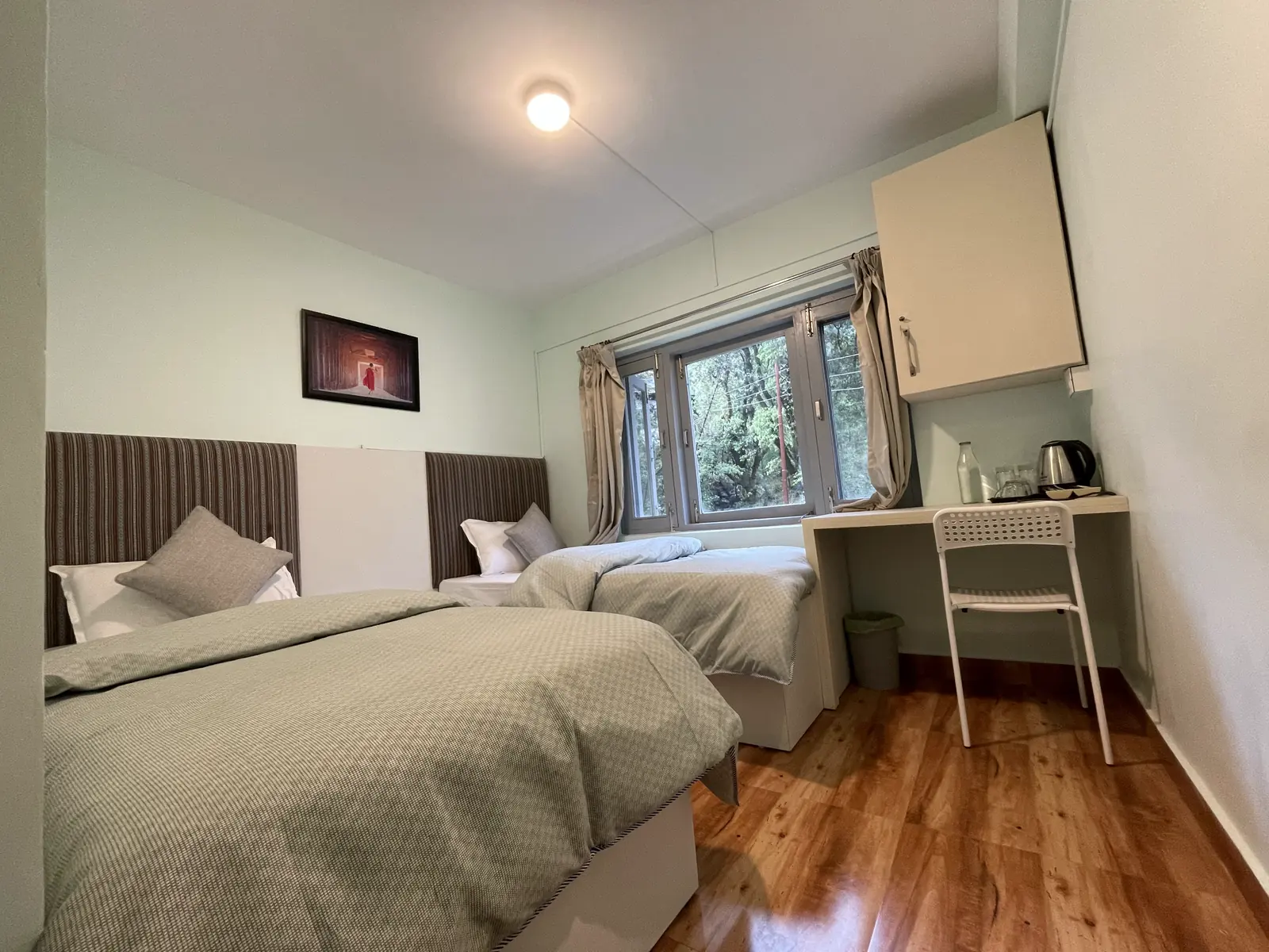 A twin room with two single beds, a window onto the trees and a desk with a kettle