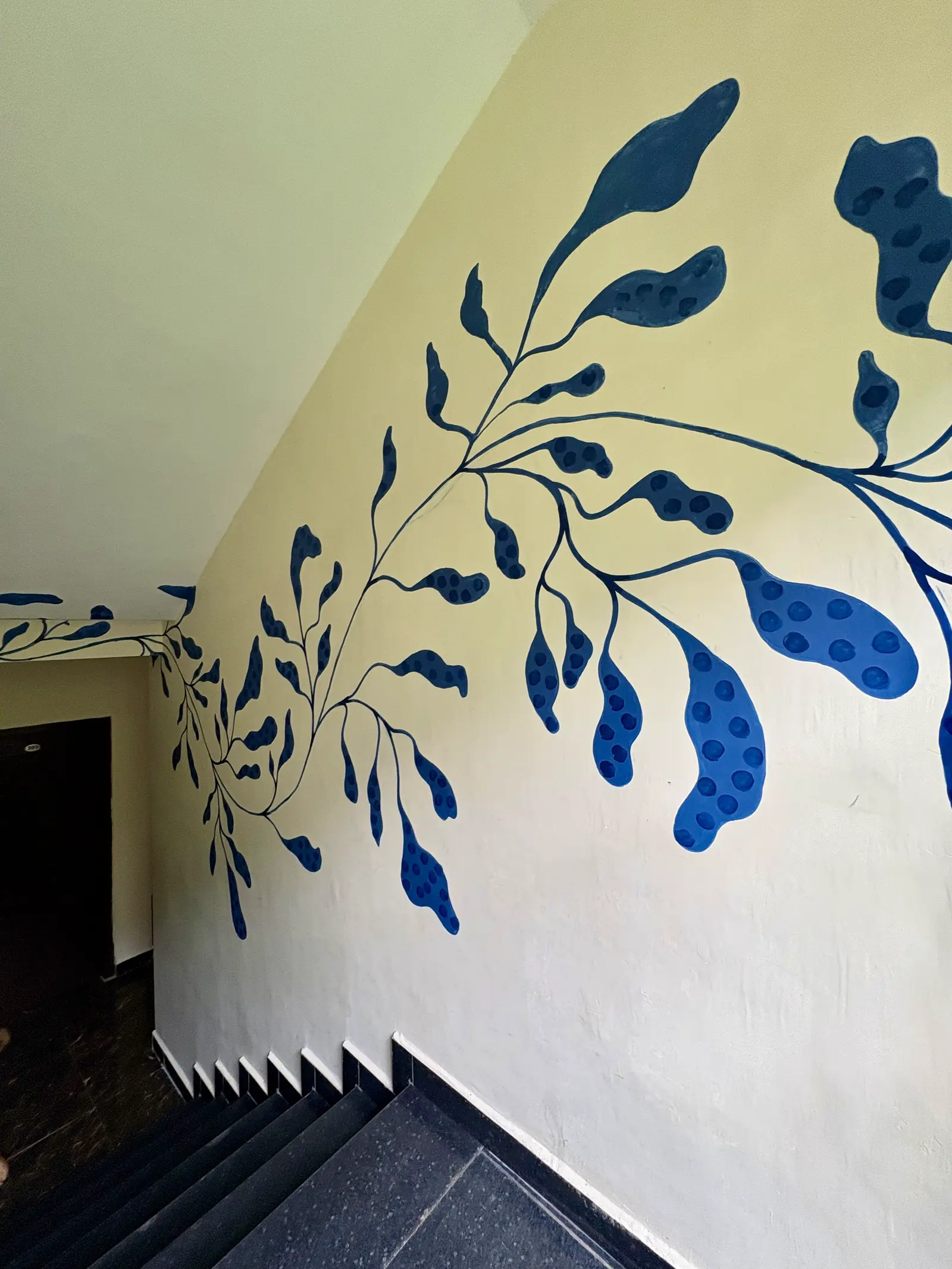A large blue leaf mural spanning the stairwell wall above dark stone steps