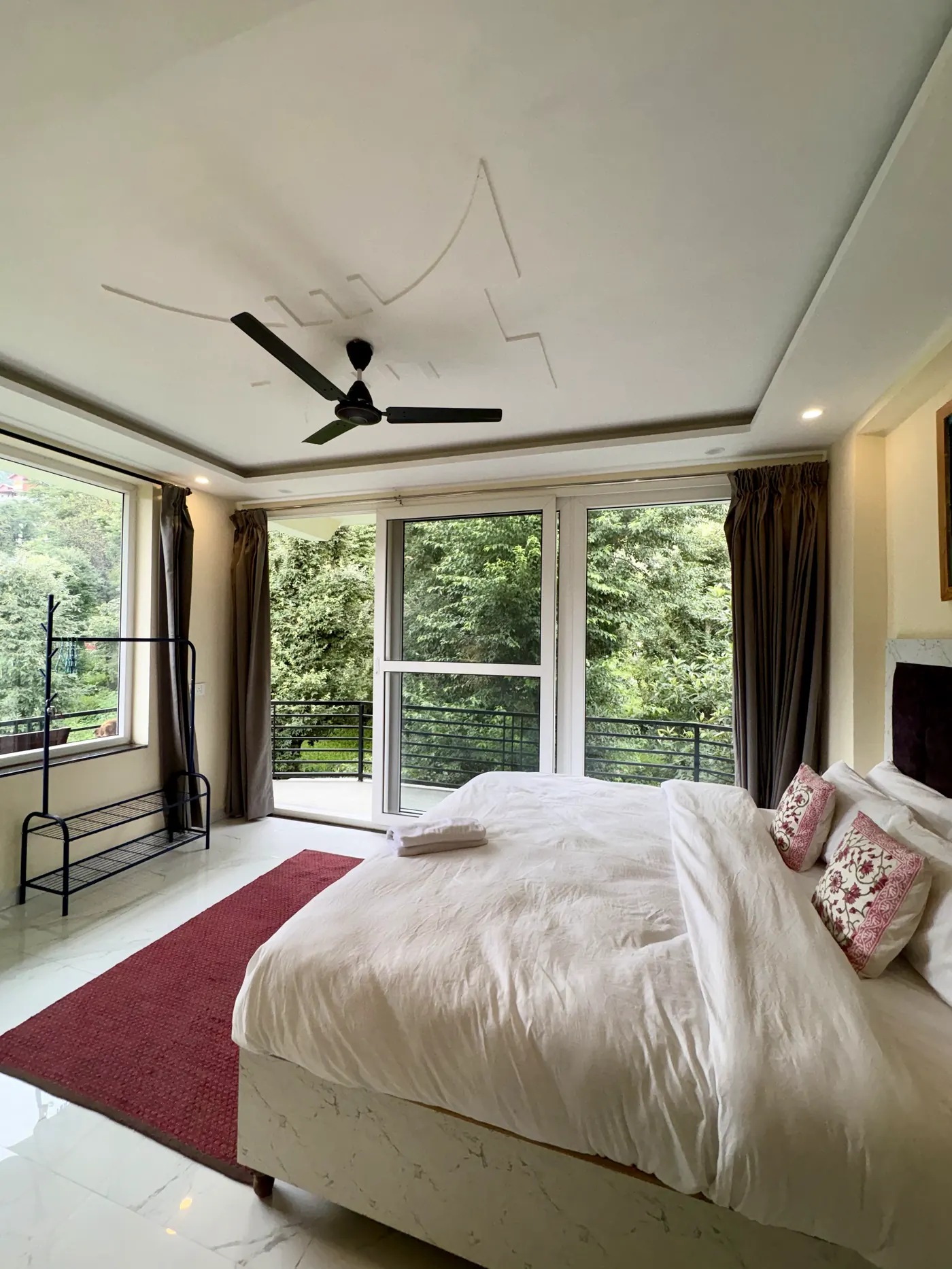 The superior studio with a red rug, luggage rack and glass doors onto the balcony
